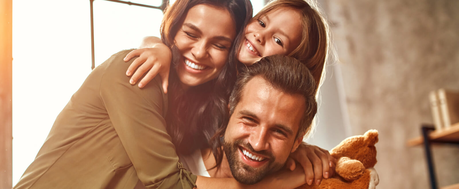 Young family hugging and smiling at the camera